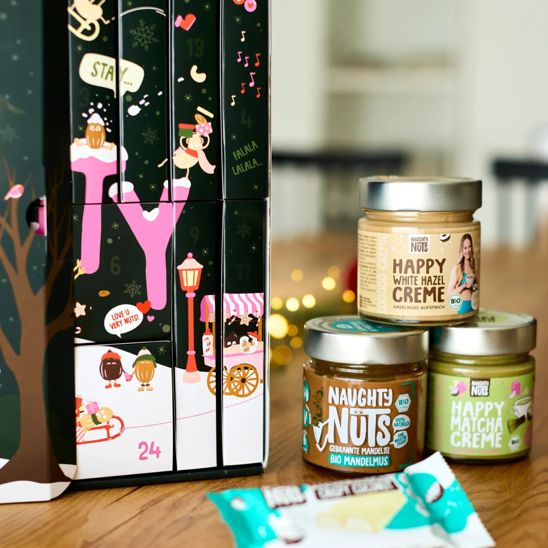 Adventskalender Deluxe 2026 mit drei Naughty Nuts Nussmus Gläsern auf einem Holztisch